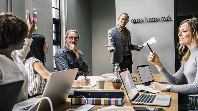 dois homens de cinza, um de pé e outro sentado com a mão no queixo, passando o processo de treinamento